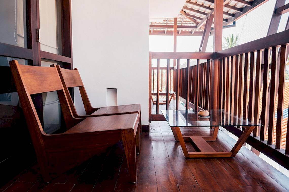 Zwei Holzstühle und ein Glastisch auf dem Balkon des Goldi Sands Hotels.