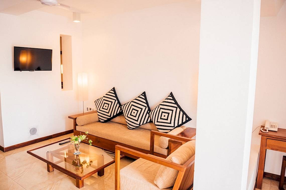 Wohnbereich im Goldi Sands Hotel mit Sofa, Couchtisch und Fernseher an der Wand.