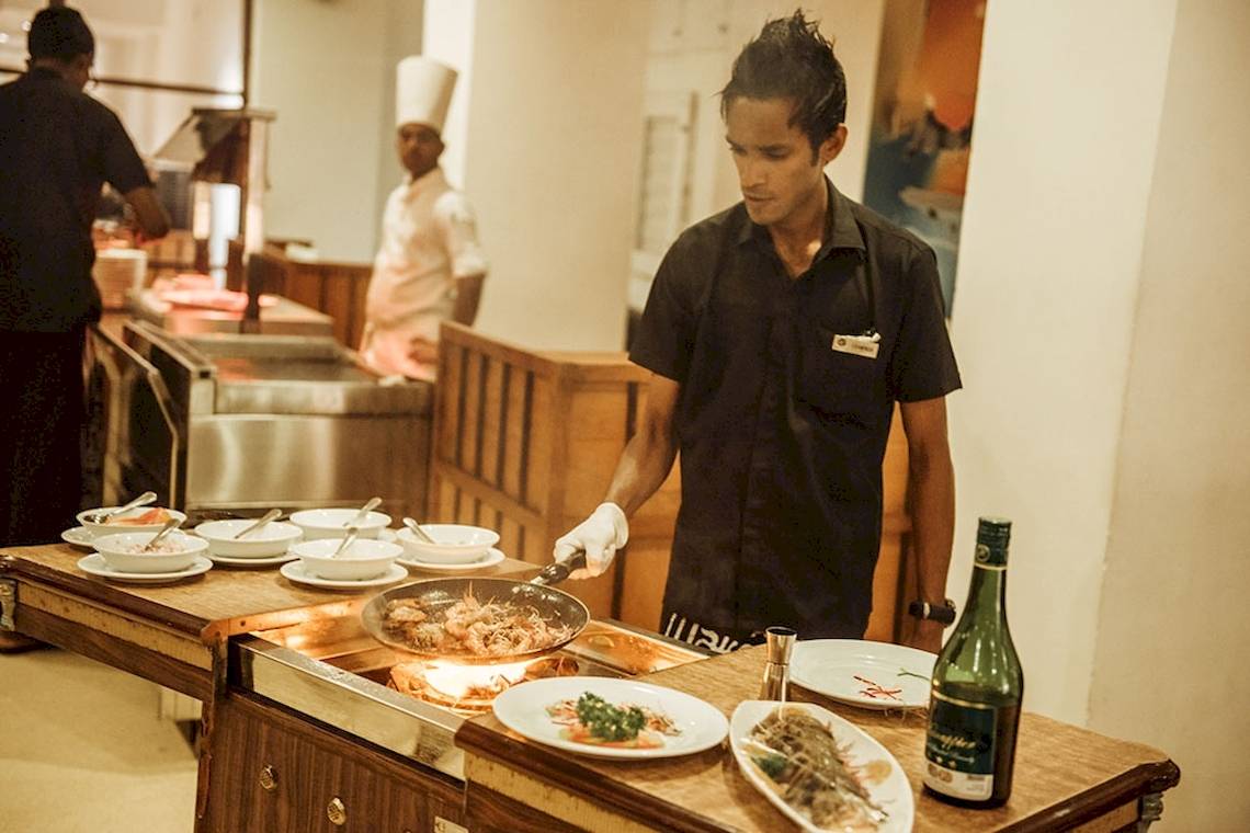 Koch in der Küche des Goldi Sands Hotels, der eine Pfanne mit Garnelen brät.