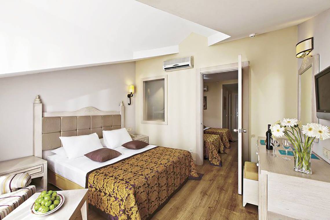 Schlafzimmer im Adalya Bliss Hotel mit einem Doppelbett, zwei Nachttischen, einer Couch und einer Kommode.