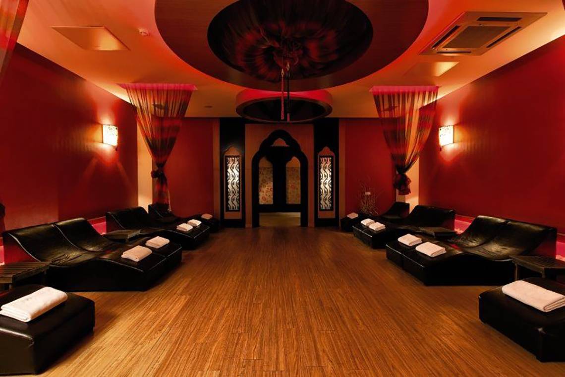 Innenbereich des Adalya Bliss Hotel mit roten Wänden, schwarzen Lederliegen und weichen weißen Handtüchern.