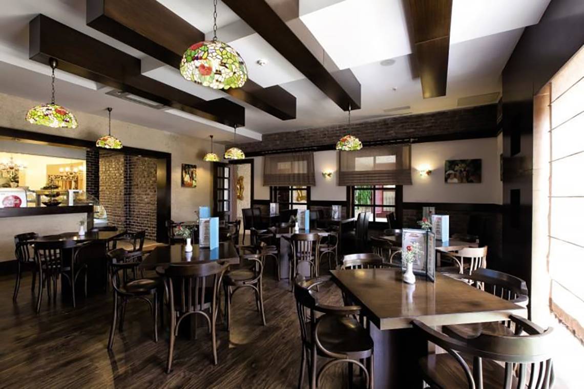 Innenbereich des Restaurants im Adalya Resort & Spa mit Holzboden, Holztischen, Stühlen und Tiffany-Lampen.