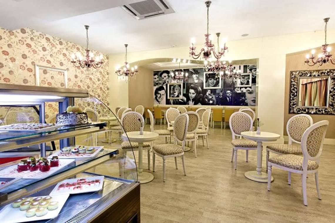 Innenbereich des Adalya Bliss Hotels mit Tischen, Stühlen und Desserts.