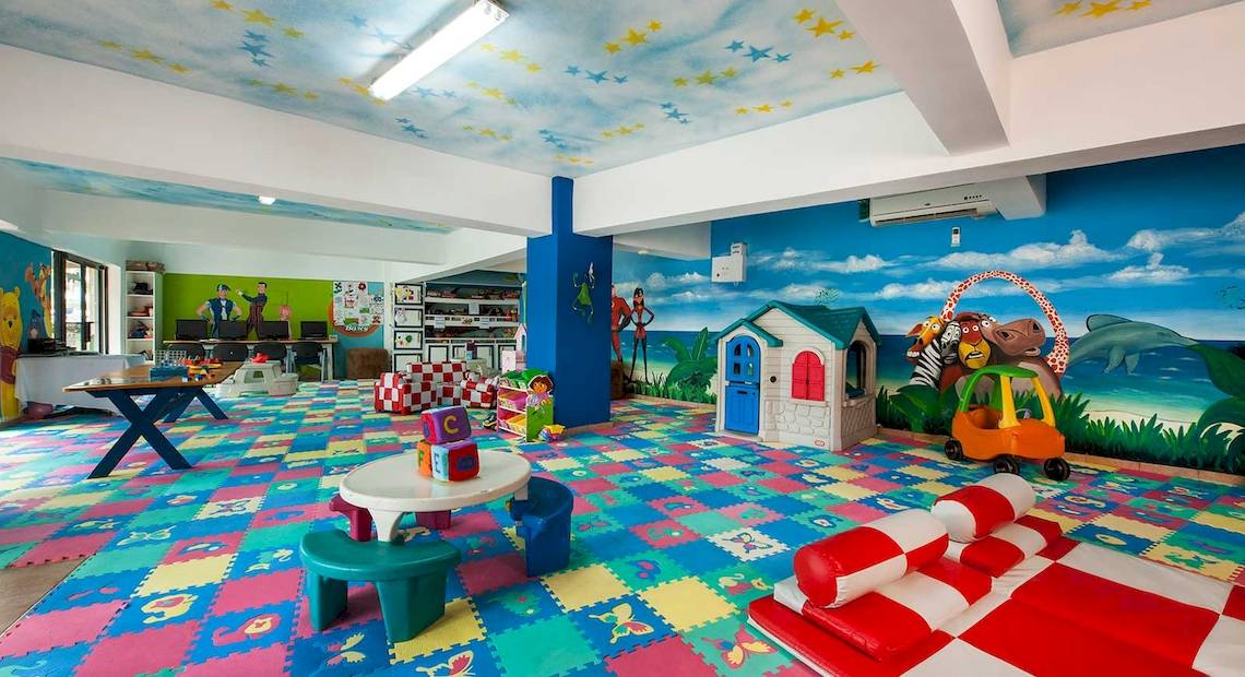 Kinderspielzimmer im Occidental Caribe Hotel mit bunten Bodenfliesen, Spielzeug und Wandmalerei.