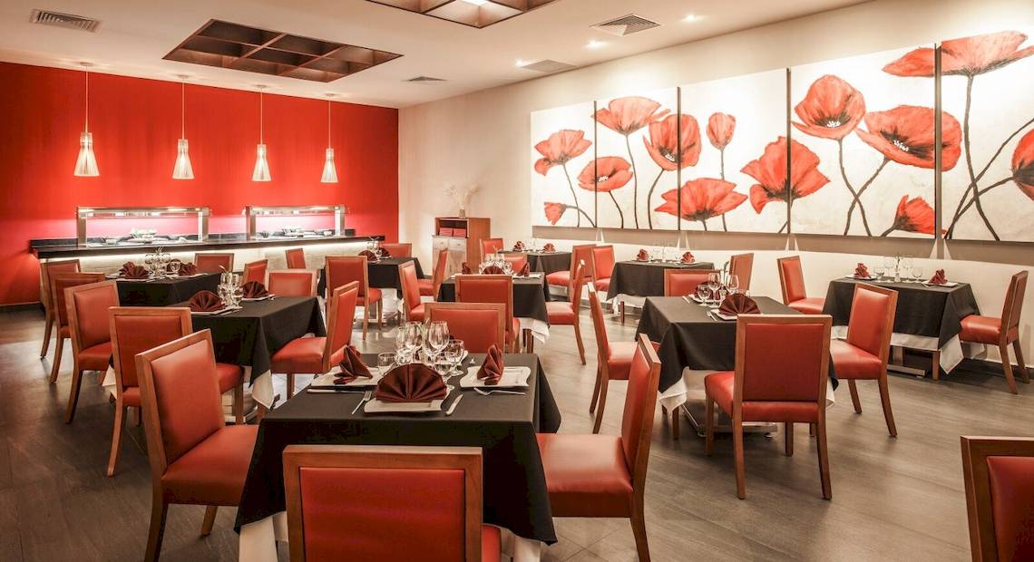 Innenansicht des Restaurants im Allegro Playacar Hotel mit roten Wänden und Tischdekoration.