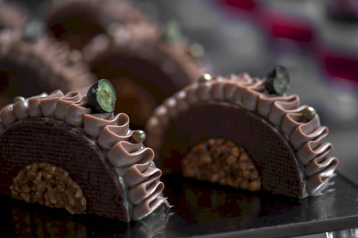Nahaufnahme von Schokoladenkuchen der Ikones Seafront Luxury Suites mit gehackten Walnüssen und grüner Marzipan-Dekoration.