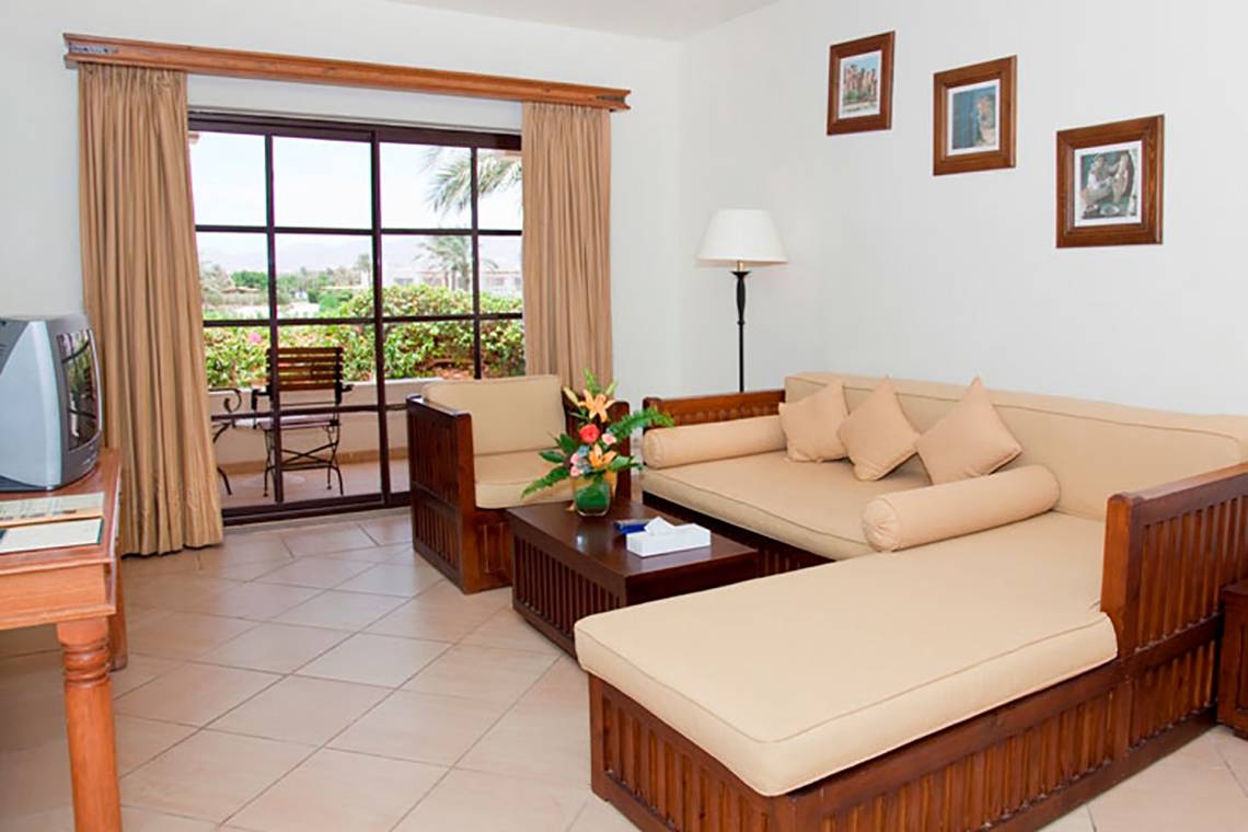 Wohnbereich des Sharm Plaza Hotels mit Sofa, Tisch, Fernseher und Glastür.