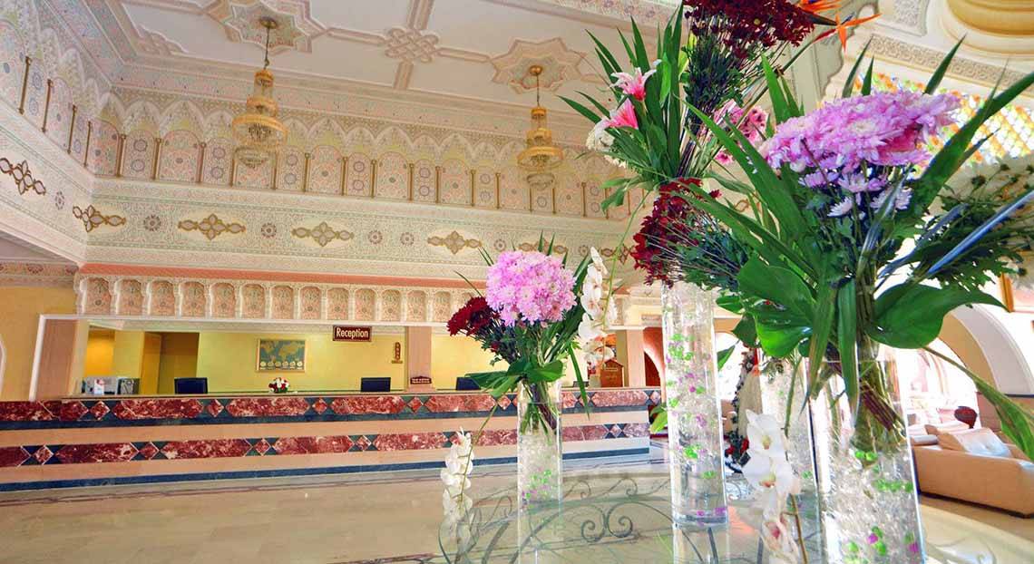 Lobby des Pickalbatros Alf Leila Wa Leila Resorts mit großen Blumenvasen und Rezeptionstresen.