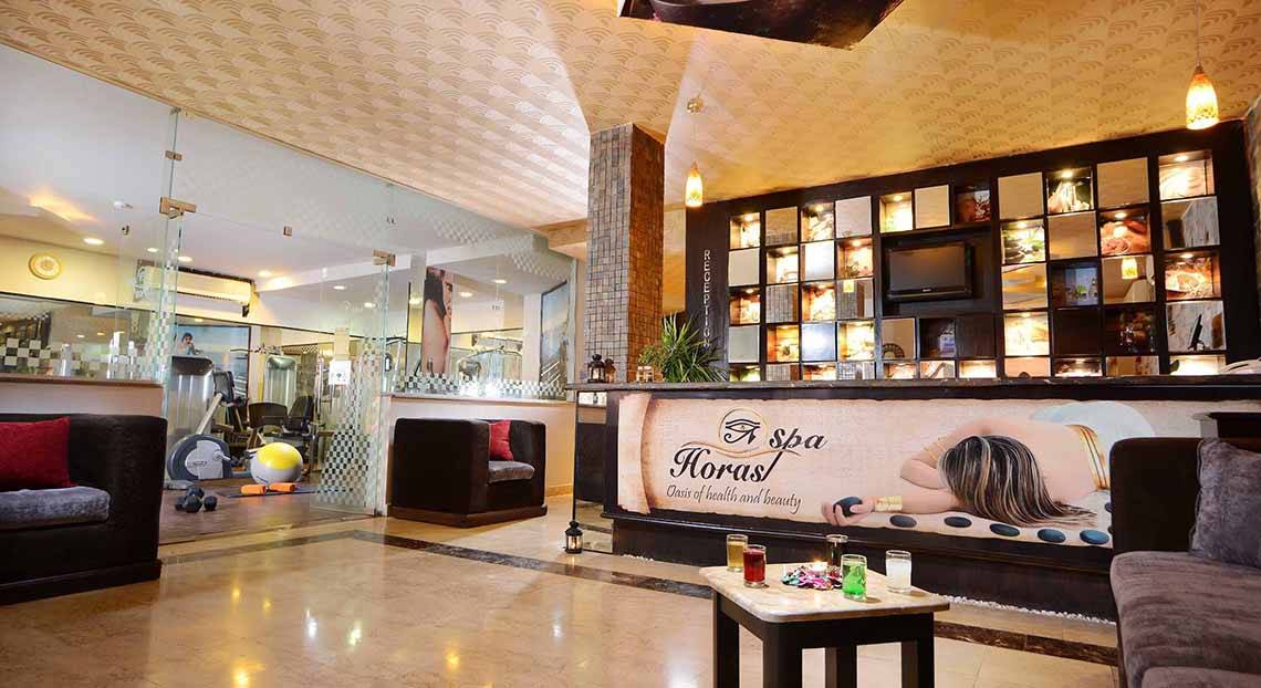 Lobby des Pickalbatros Alf Leila Wa Leila Resorts mit Couch, Tisch und Wellness-Werbetafel.