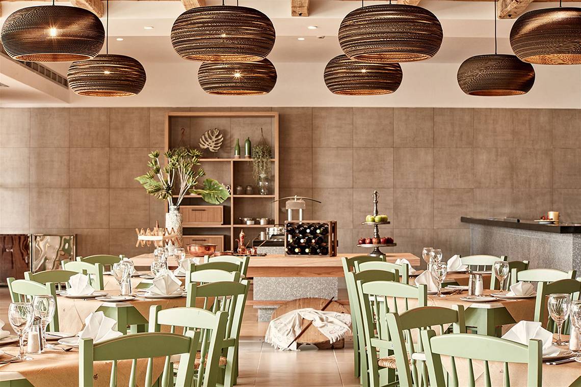 Innenansicht des Restaurants des Atlantica Mikri Poli Kos Hotels mit grünen Stühlen und Holztischen.