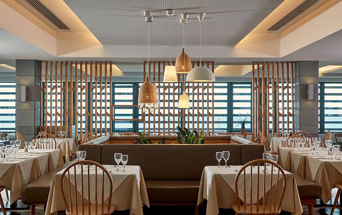 Restaurantbereich des Atlantica Mikri Poli Kos Hotels mit Tischen, Stühlen und Fenstern.