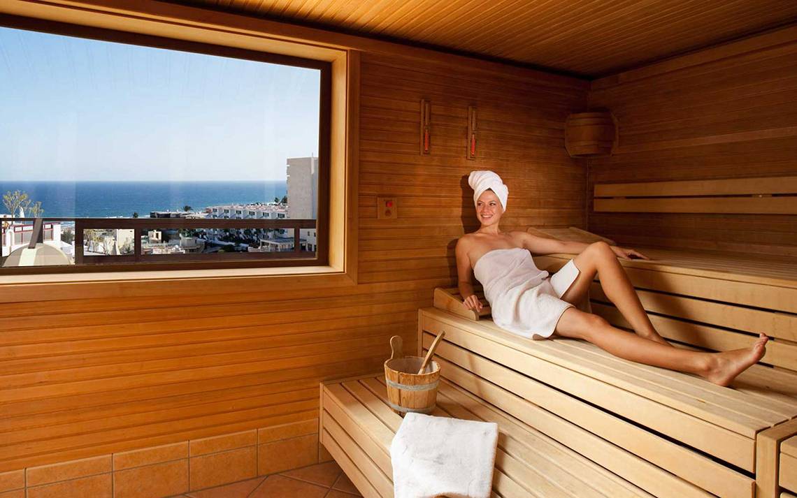 Frau im Bademantel in der Sauna mit Blick auf das Meer im Seaside Sandy Beach Hotel.