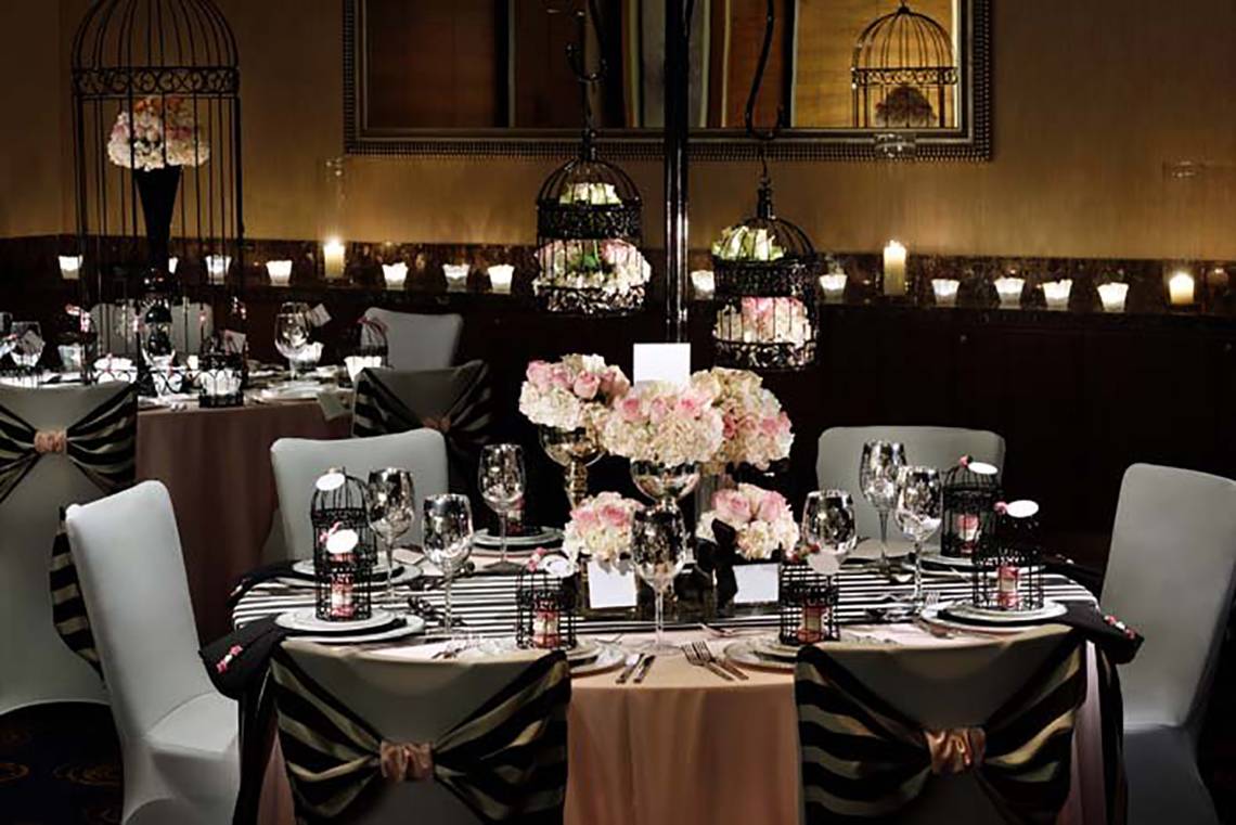 Bankettsaal-Arrangement im Mövenpick Hotel Jumeirah Beach mit rosa Blumen und Käfigen.