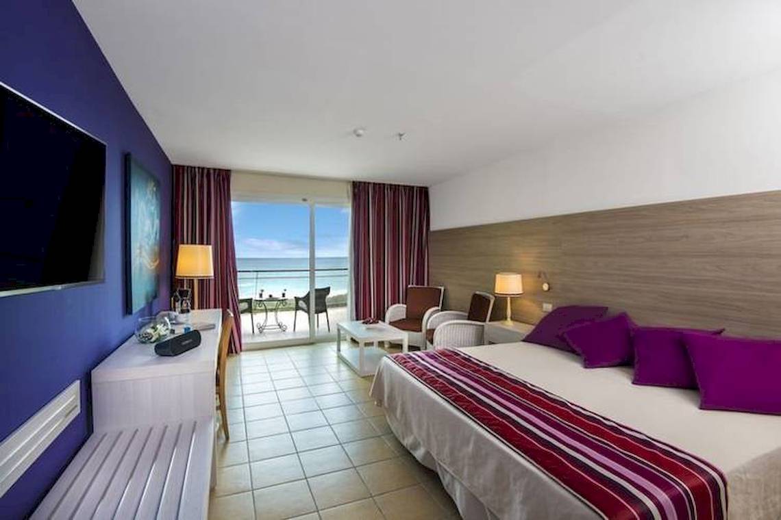 Innenansicht eines Hotelzimmers im Blau Varadero mit Bett, Möbeln und Aussicht auf den Ozean.