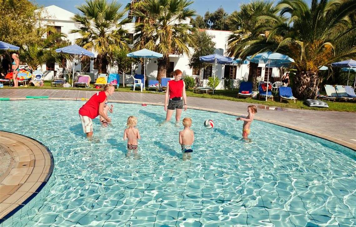 Kinder schwimmen im Pool im Atlantica Marmari Beach Hotel mit Sonnenschirmen und Liegestühlen im Hintergrund.