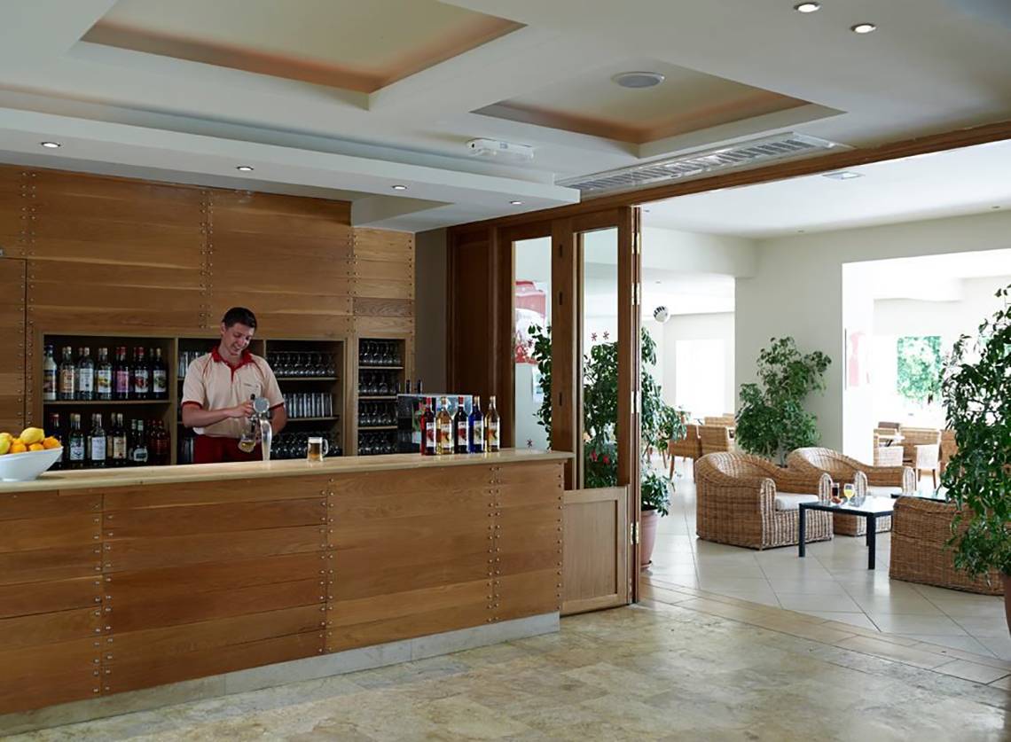 Barbereich im Atlantica Holiday Village Kos mit Barkeeper und gefüllten Flaschen
