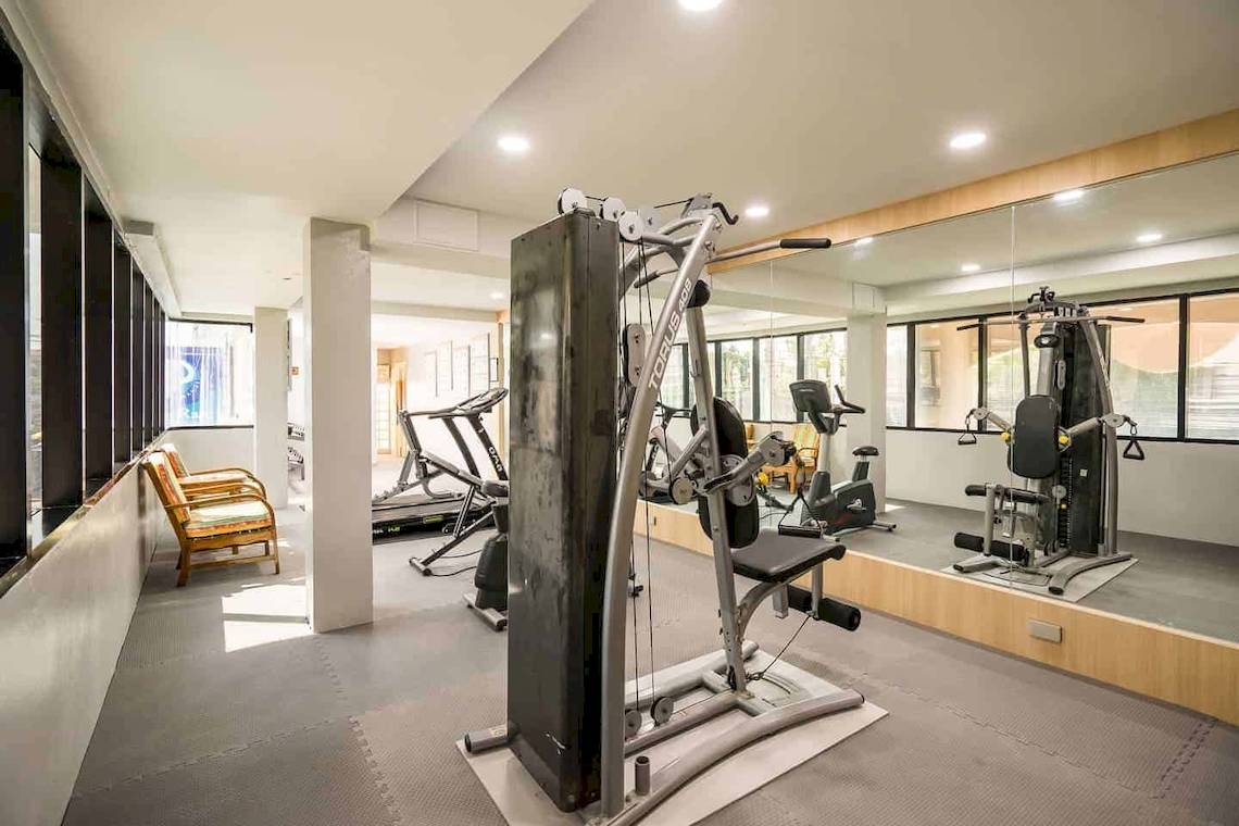 Fitnessraum im Chaba Samui Resort mit verschiedenen Geräten und Fenstern.