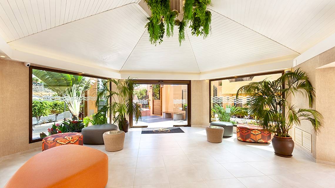 Der Eingangsbereich des Tagoro Family & Fun Costa Adeje Hotels mit Innendekoration, Pflanzen und Möbeln.