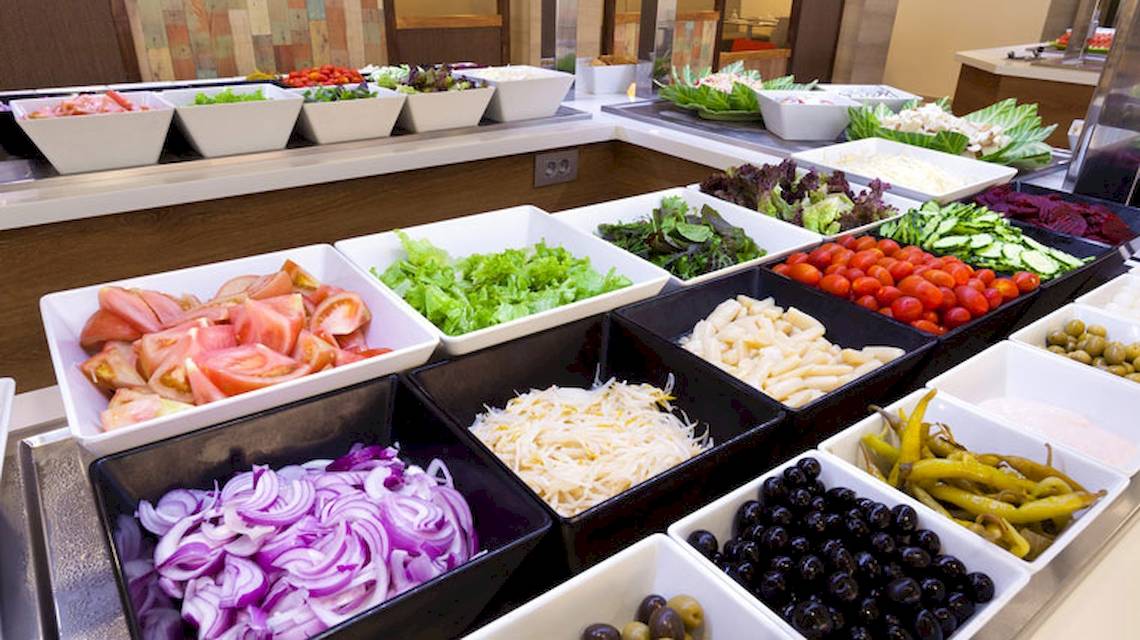 Buffet im Hotel Tagoro Family & Fun Costa Adeje mit verschiedenen Salaten, Tomaten, Gurken, Oliven und anderen Zutaten.