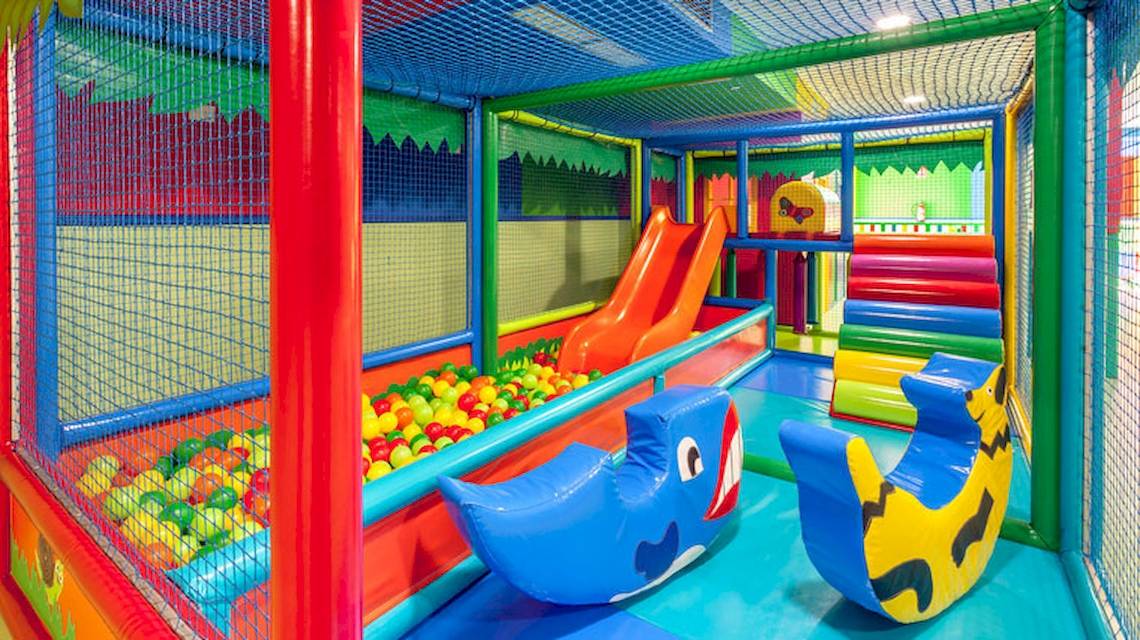 Kinderspielplatz im Tagoro Family & Fun Costa Adeje mit bunten Spielgeräten und einer Rutsche.