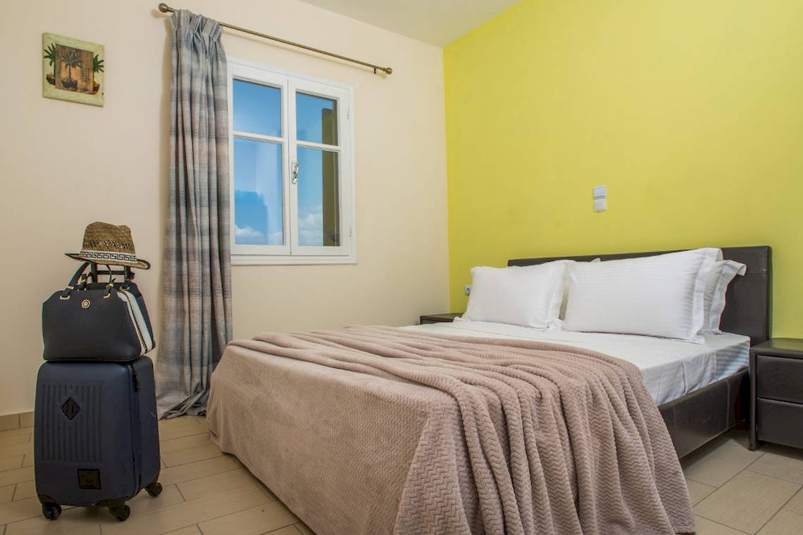 Ein Bett mit einer Decke und Kissen in einem Zimmer im Naxos Palace Hotel.