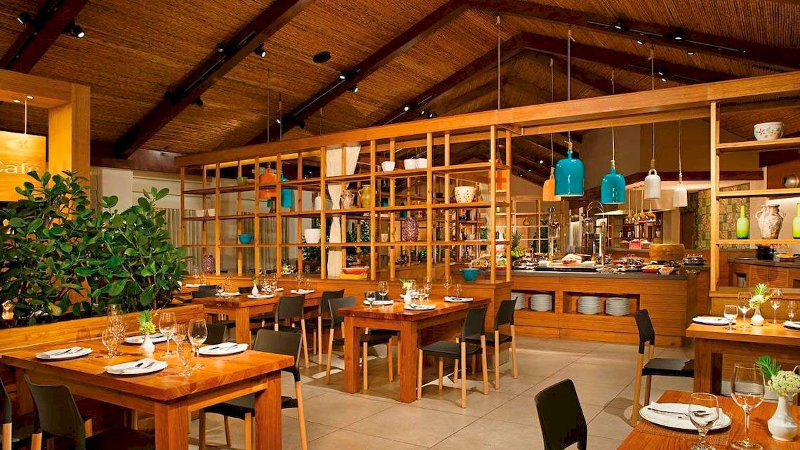 Innenraum des Restaurants Secrets Papagayo Costa Rica mit Holztischen, Stühlen und offenen Regalen.
