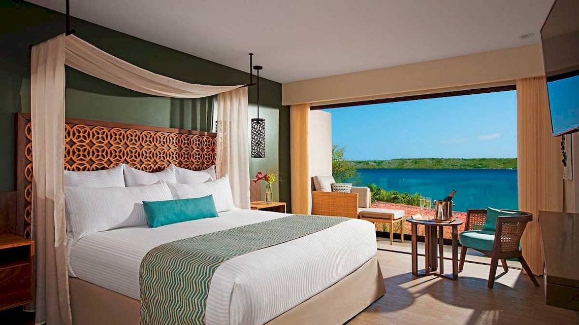 Suite mit Meerblick im Secrets Papagayo Costa Rica Hotel, inklusive Bett, Sitzbereich und Meersicht.