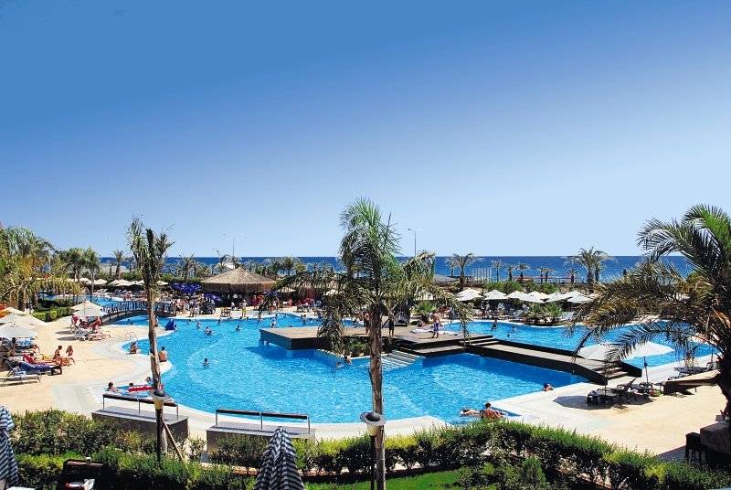 Außenpoolbereich des Long Beach Alanya Hotels mit vielen Gästen und Palmen.