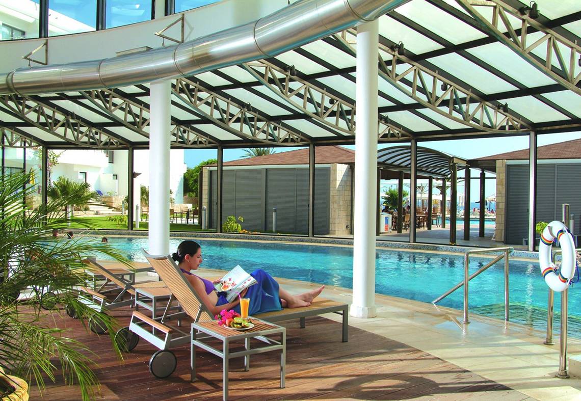 Frau liest Buch am Pool im Louis Ledra Beach Hotel