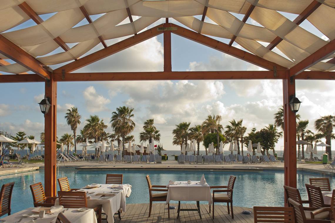 Terrasse des Louis Ledra Beach Hotels mit Blick auf den Pool und das Meer.