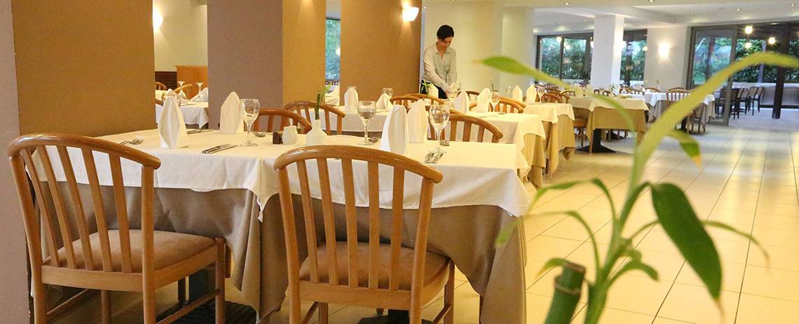 Innenansicht des Restaurants im Minos Mare Hotel mit gedeckten Tischen und Stühlen.