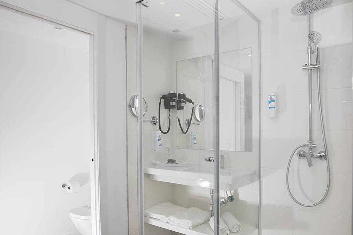 Badezimmer im Alua Leo Hotel mit Glasdusche, Waschbecken und Toilette.
