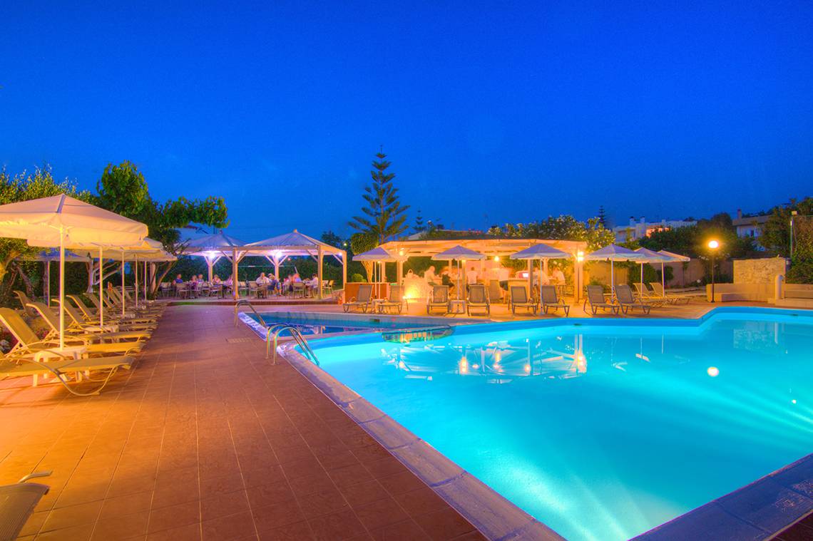 Poolbereich im Solimar Dias Hotel bei Nacht mit beleuchteten Schirmen und Lounge-Stühlen.