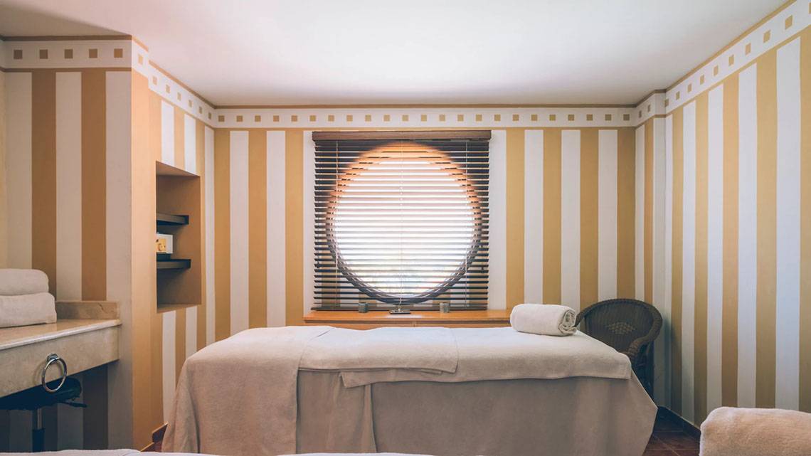 Massageraum im Iberostar Laguna Azul Hotel mit Rundfenster und gestreiften Wänden.