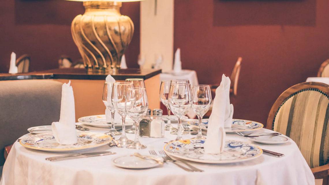 Ein gedeckter Tisch im Speisesaal des Iberostar Laguna Azul Hotels mit Tellern, Gläsern und Servietten.