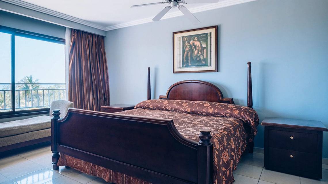 Schlafzimmer im Iberostar Laguna Azul Hotel mit Bett, Nachttischen und Gemälde an der Wand.