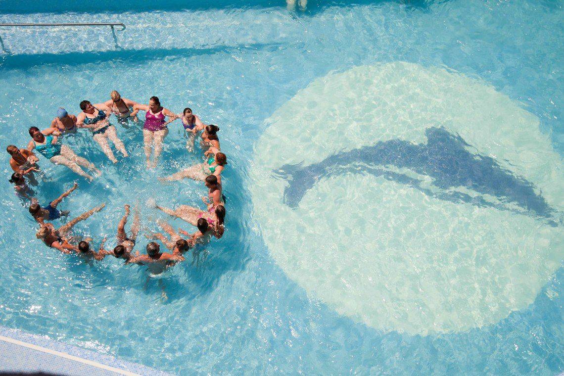 Gruppe von Schwimmern im Pool des Don Gregory by Dunas Hotel, alle halten Händchen.