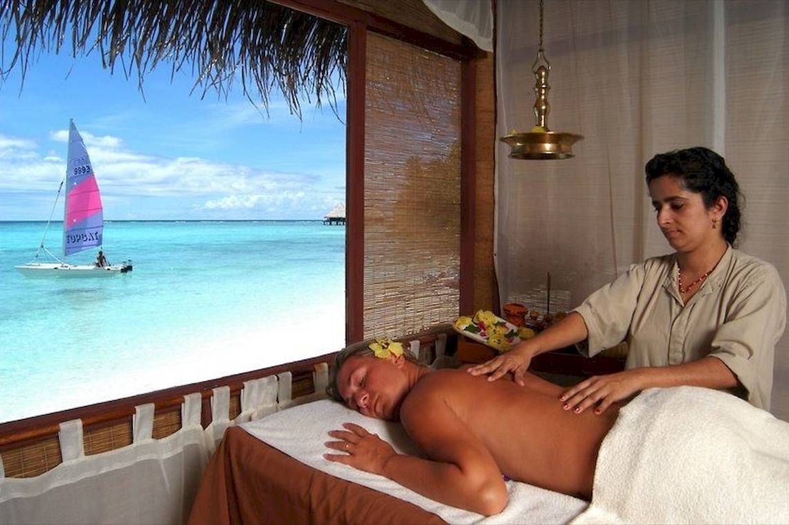 Eine Frau massiert einen Mann am Strand im Hotel Adaaran Club Rannalhi.