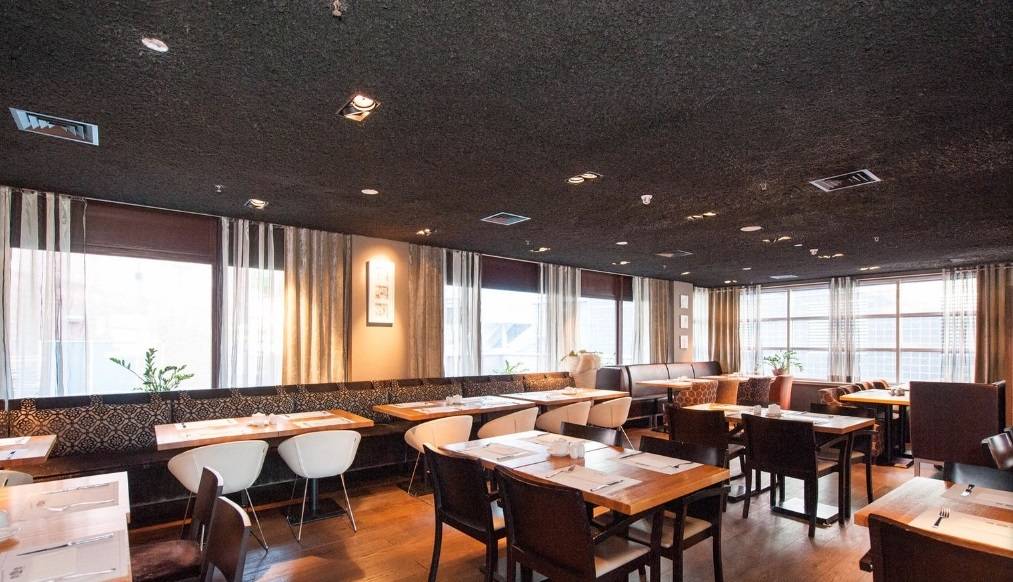 Innenansicht des Restaurants des XO Hotels Blue Tower mit Tischen und Stühlen.
