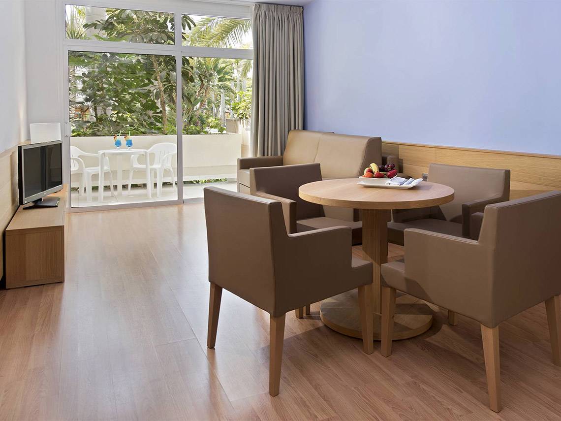 Wohnbereich des Tabaiba Princess Hotels mit Tisch, Stühlen und Fernseher.