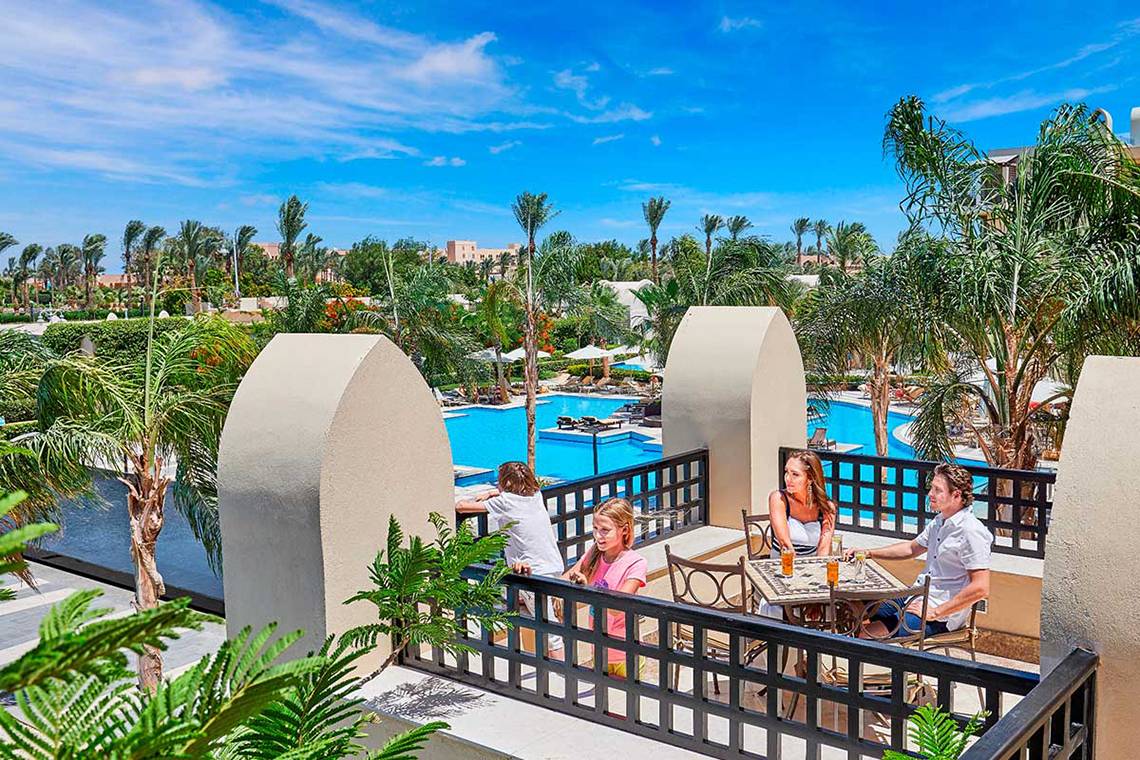 Familie genießt Ausblick auf den Pool vom Hotelbalkon aus