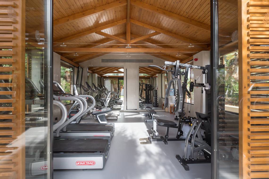 Innenansicht des Fitnesscenters im Cretan Malia Park Hotel mit Laufbändern und Kraftgeräten.