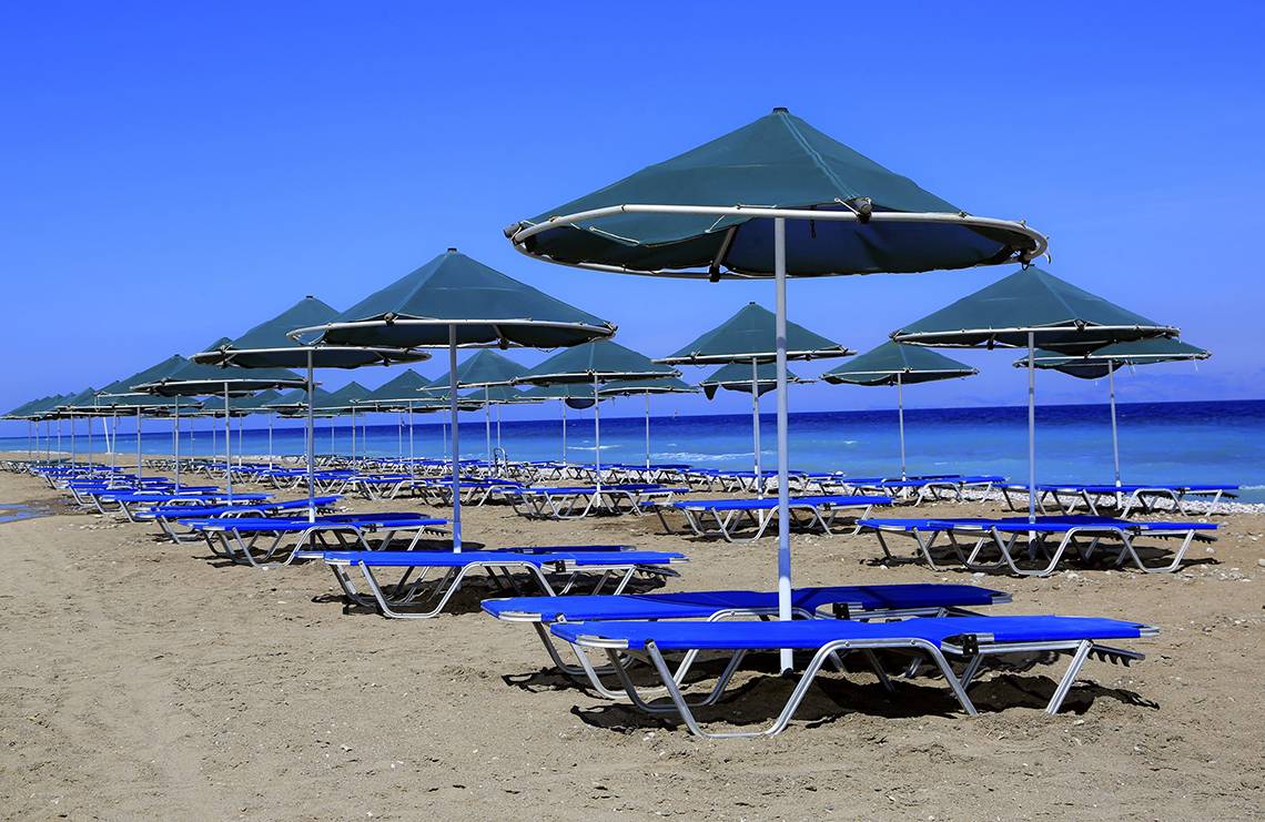 Reihe von Sonnenliegen und Sonnenschirmen am Strand des Blue Bay Beach Resorts.