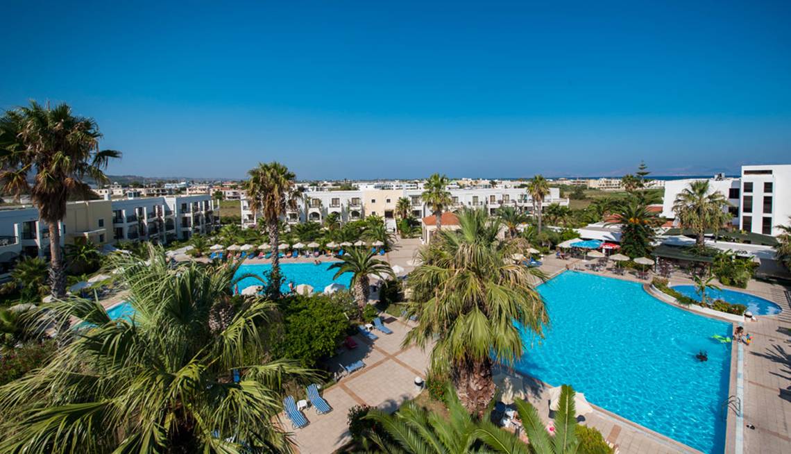 Hotelanlage mit Pool und Palmen von oben gesehen.