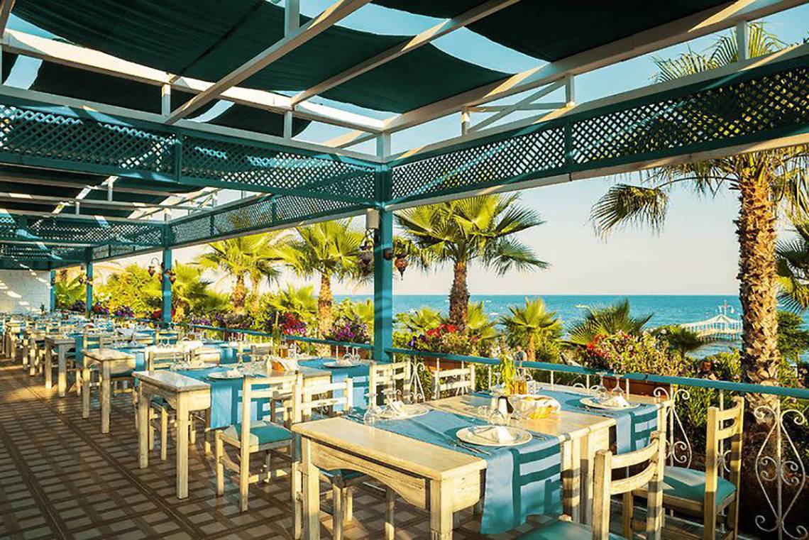 Außenterrasse des Turan Prince Hotels mit Blick auf das Meer und Palmen.