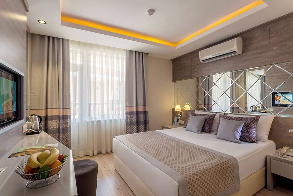 Schlafzimmer im Turan Prince Hotel mit Bett, Obstschale und Fernseher.