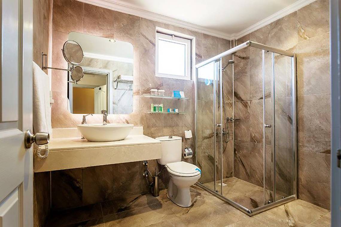 Badezimmer im Turan Prince Hotel mit Waschbecken, Spiegel, Toilette und Glasdusche.