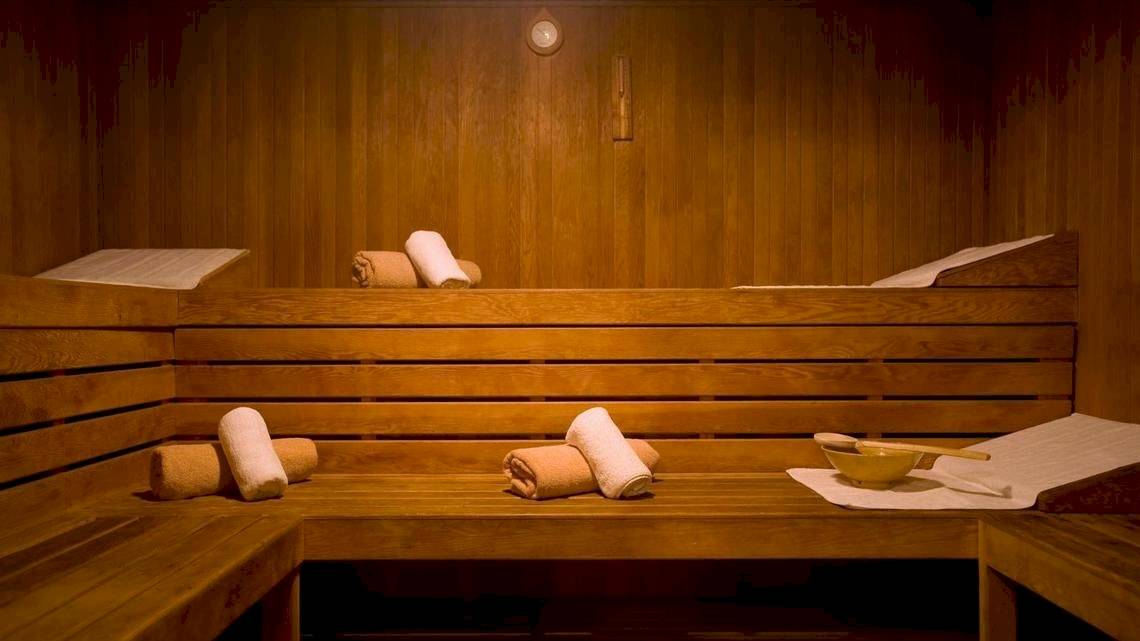 Saunabereich im Le Meridien N'Fis Hotel mit Holzbänken, Handtüchern und einem gelben Schüssel.