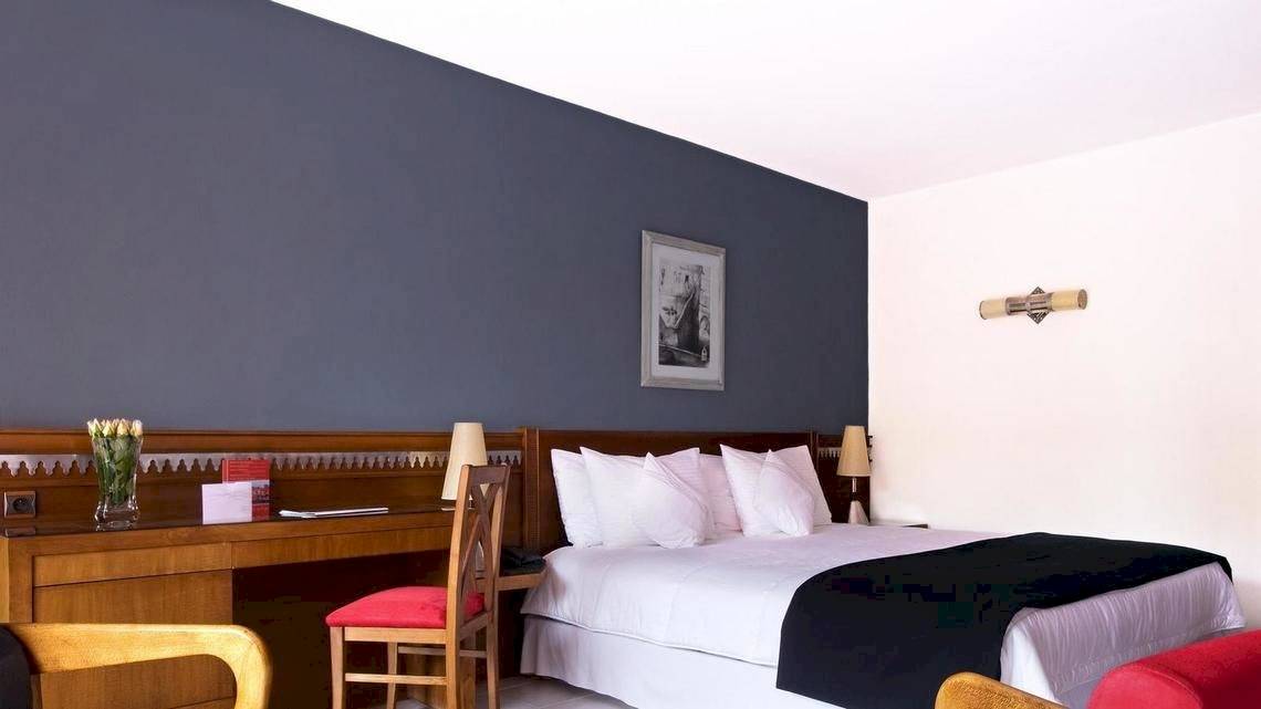 Le Meridien N'Fis Hotelzimmer mit Bett, Schreibtisch und Stühlen.