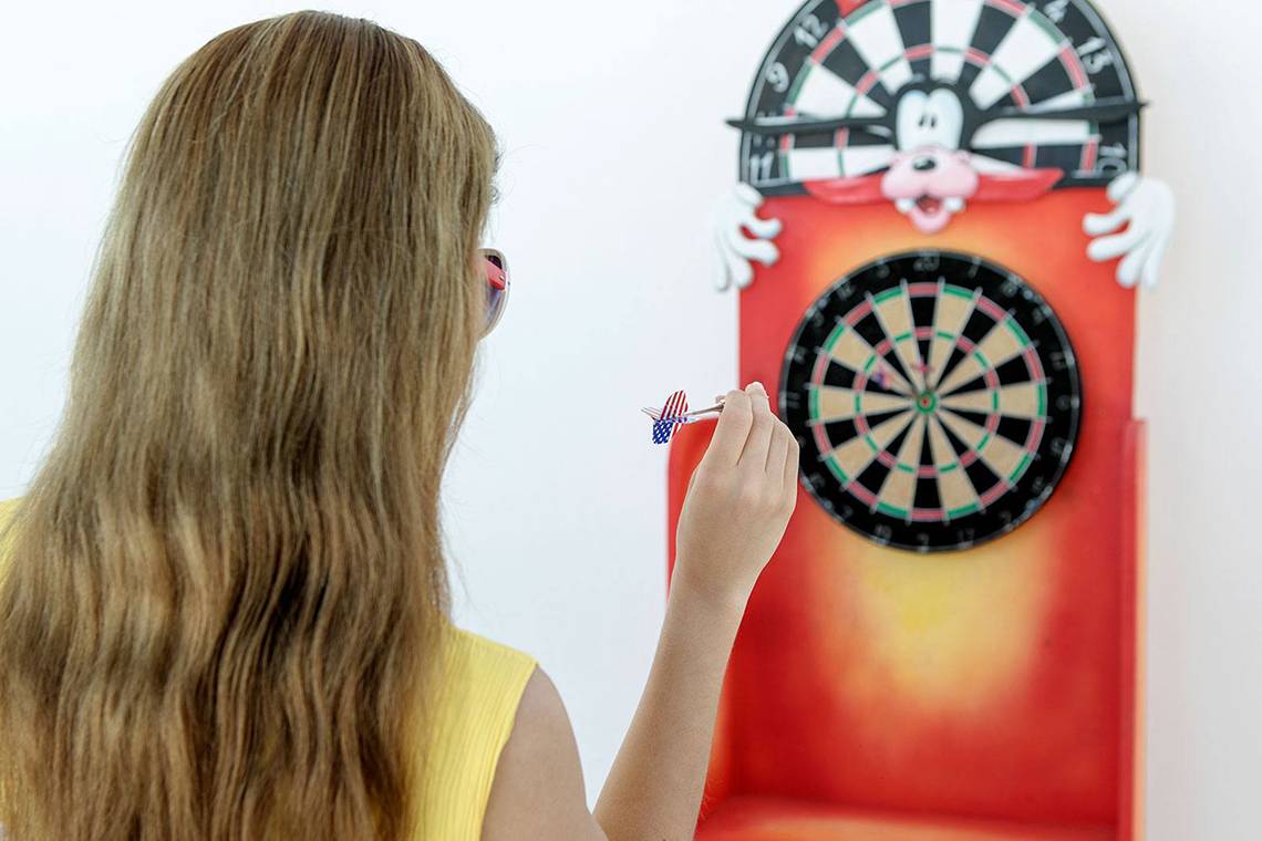 Eine Frau wirft einen Pfeil auf eine Dartscheibe mit Mickey Mouse.